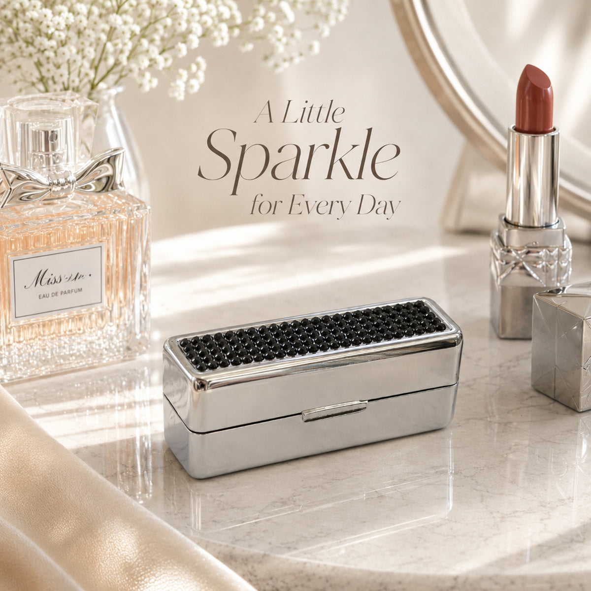Black rhinestone lipstick case on vanity with lipstick and perfume
