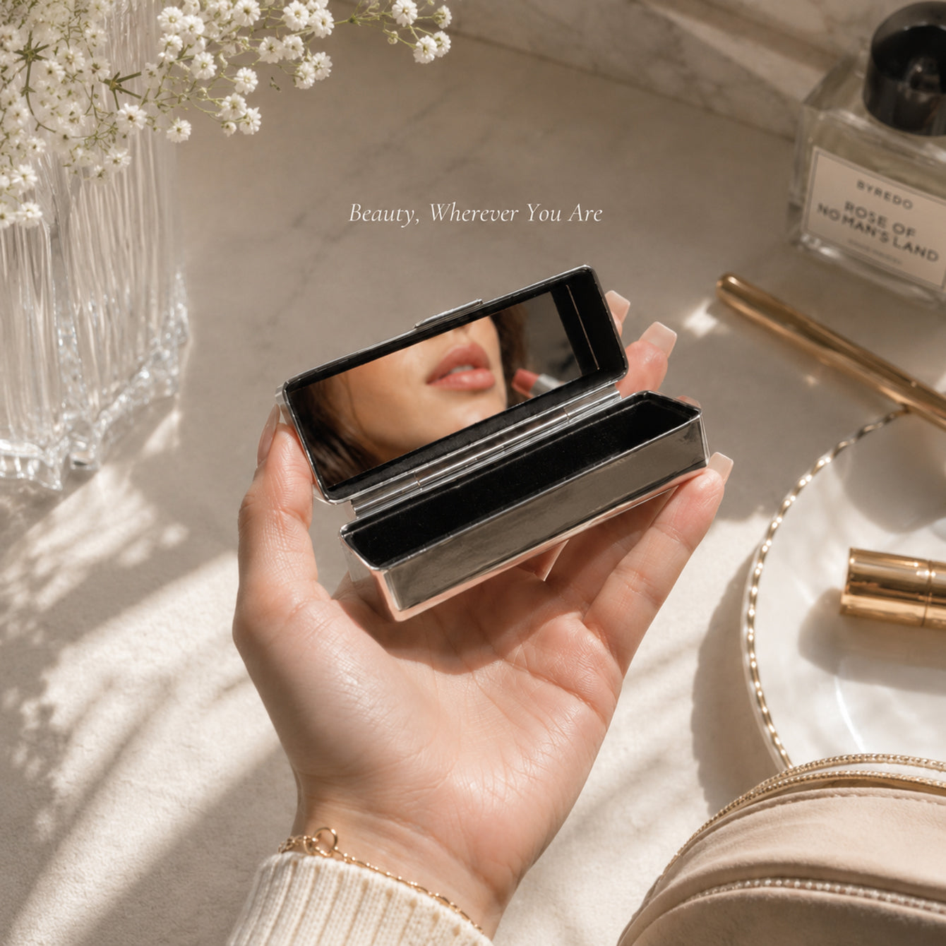Woman holding open rhinestone lipstick case with built-in mirror